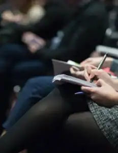 Business professionals taking notes at a conference session.